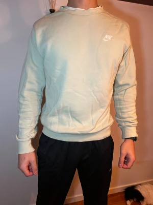 Ljusgrön Nike sweatshirt - Snygg ljusgrön sweatshirt från Nike med broderad logga på bröstet. Tröjan har rund hals, ribbade muddar och är tillverkad i mjuk bomullsmix. Perfekt för chill dagar och enkel att matcha med jeans eller joggers.