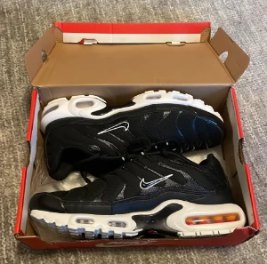 Nike Air Max Plus Tn Svart/Vit - Nike Air Max Plus Tn sneakers i svart mesh och syntet med vita detaljer och tydlig Tn-logga på hälen. Skorna har en chunky vit sula med synliga Air Max-enheter och svarta snören med vita accenter. Perfekt för dig som gillar streetwear och sportig stil.
