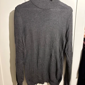 Grå polotröja från DeFacto Studio XS - Snygg grå polotröja från DeFacto Studio i storlek XS. Tröjan är ribbstickad med lång ärm och har en klassisk polokrage. Perfekt för dig som gillar stilrena och enkla plagg med en modern touch. Materialet är mjukt och tunt, vilket gör den skön att bära.