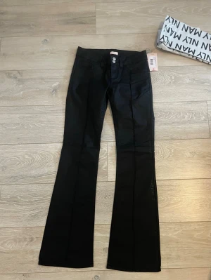 Svarta coated jeans från Nelly, stl 36 - Jättesköna jeans från Nelly.HEEELT nya med prislappen på!🤩 tyvärr var de för stora för mig och kan inte skicka tillbaka. De är endast använda en gång då jag provade dem. Inga skador eller märken, utan helt nya jeans.  Originalpriset: 699kr 
