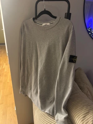 Stone Island sweatshirt - Grey Melange - L - Säljer en clean grå sweatshirt från Stone Island i storlek L. Tröjan har rund hals, lång ärm och den klassiska svarta patchen med gul broderad logga på vänster ärm. Materialet är mjuk bomull som är skön mot huden och passar perfekt till jeans eller cargo. Nypris: 2899:- 