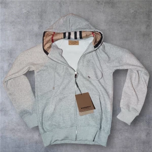 Grå zip-hoodie från Burberry - Snygg grå hoodie från Burberry med dragkedja och klassisk logga broderad på bröstet. Huva med ikoniskt Burberry-mönster på insidan och justerbara snören med metalländar. Mjuk bomullsblandning och ribbade muddar vid ärmar och nederkant. Perfekt för chill dagar.