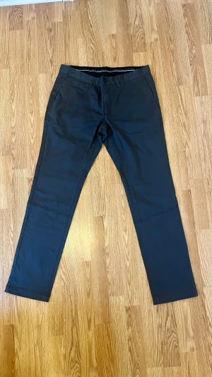 Svarta kostymbyxor från Bläck, strl 34 - Snygga svarta kostymbyxor från Bläck, modell Jarvis slacks. Klassisk rak passform med diskreta fickor fram och bak, midja med hällor för bälte. Perfekta för en clean och stilren look. Materialet är mjukt och känns bekvämt mot huden.