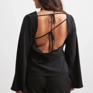 Blus med snörning i ryggen  - Snygg och elegant svart blus från NA-KD. Snygg detalj med snörning i ryggen! Blusen är storlek 34 och är aldrig använd, bara testad men lappen är inte kvar🤎