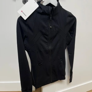Svart träningsjacka från Lululemon - Som tidigare hjälper jag min syster få kläder hon inte använder eller för små sålda så här är en svart träningsjacka från Lululemon med snygga sömdetaljer och två fickor med dragkedja. Jackan har lång ärm med tumhål och hel dragkedja framtill. Perfekt för dig som gillar sportig och clean stil. Priset kan diskuteras 👍🏻💛
