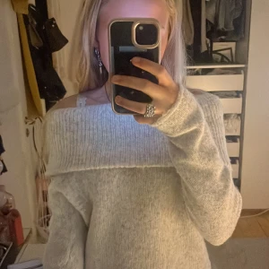 Offshoulder stickad tröja Gina Tricot - Supermysig ljusgrå stickad offshoulder-tröja från🤭 Gina Tricot. Tröjan har bred ribbad kant upptill som sitter snyggt över axlarna och långa ärmar🤗har använt cirka 5 gånger tror jag 
