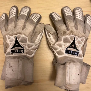 Select 93 Elite V21 målvaktshandskar - Säljer ett par välanvända men fortfarande funktionsdugliga Select 93 Elite V21 målvaktshandskar. Dessa handskar är kända för sin komfort, grepp och hållbarhet, och har varit ett pålitligt val under många matcher.  Skicket är använt – se bilder för detaljer. Slitna i handflatorna och något smutsiga, men passar perfekt som ett extra par för träning eller som backup.  Storlek: 9.5 Nypris: 979kr  Skicka ett meddelande vid intresse! Pris kan diskuteras 