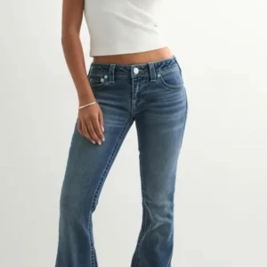 True Religion jeans - True religion ultra low waist. Snygga blå jeans från True Religion med klassisk bootcut-passform och ikoniska bakfickor med broderad logga. Jeansen har normal midja, dragkedja och knapp framtill. Materialet är slitstarkt denim i bomull med lätt tvättad look.