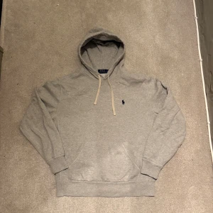 Grå Polo Ralph Lauren hoodie - Säljer min Ralph Lauren hoodie då den inte kommer till användning. Hör gärna av dig om funderingar eller prisförslag!
