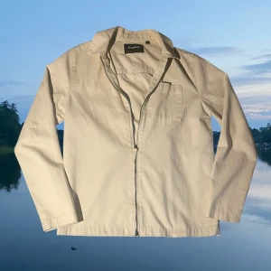 Beige overshirt från Lyle & Scott - Snygg beige overshirt från Lyle & Scott med klassisk krage, bröstficka och hel dragkedja framtill. Perfekt för lager-på-lager och enkel att matcha med jeans eller chinos. Kom med bud eller frågor!