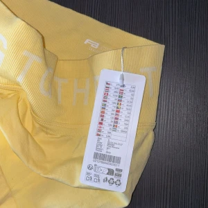 Gula seamless leggings från RB Sister - Snygga ljusgula seamless leggings från RB Sister med bred ribbad midja och texten 'STRNG TGTHR' i vitt. Tillverkade i mjukt och stretchigt material som passar perfekt för träning eller chill. Midjan är hög och ger en skön passform.