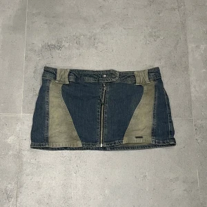 BDG jeanskjol med kontrastpaneler - Säljer en kort jeanskjol från BDG Urban Outfitters i medium. Kjolen har kontrastpaneler i beige och blått, bakfickor med BDG-logga och en synlig dragkedja framtill.