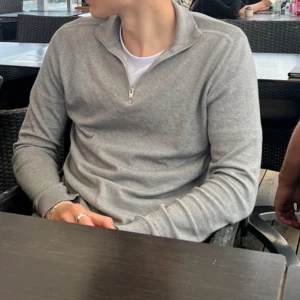 Grå half zip-tröja Selected Homme - Snygg grå långärmad tröja från Selected Homme med half zip-dragkedja och ståkrage. Tröjan är i mjuk bomullsmix och har ribbade muddar vid ärmslut och nederkant. Perfekt för lager-på-lager och chill stil.