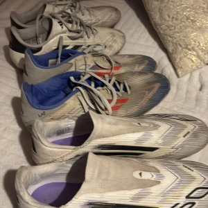 Flera par vita Adidas fotbollsskor - Säljer flera par Adidas fotbollsskor i olika modeller. Skorna är vita med svarta och röda detaljer, vissa med snörning och andra utan. Lätta och smidiga med syntetmaterial, perfekta för dig som vill ha snabbhet på planen. F50 laceless 44,5 copa44 f50 45 1/3.