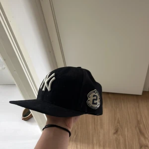Blå New Era Yankees keps - Säljer en blå New Era 59FIFTY keps med Yankees-logga framtill och broderad patch med nummer 2 på sidan. Klassisk rak skärm och MLB-logga bak. 