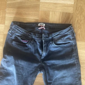 Svarta straight jeans från Hilfiger Denim - Snygga svarta jeans från Hilfiger Denim med raka ben och klassisk femficksdesign. Byxorna har Hilfigers signaturrand på myntfickan och detaljer i silver. Tillverkade i mjukt jeanstyg med normal passform och midwaist. För killar även tjejer 