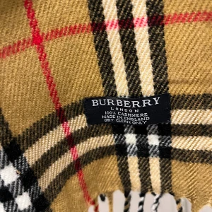 Rutig halsduk i kashmir från Burberry - Klassisk halsduk från Burberry i 100% kashmir med det ikoniska rutiga mönstret i beige, svart, vitt och rött. Mjuk och lyxig känsla, perfekt accessoar för att lyfta din outfit. Tidlös design med fransar i ändarna och märkets logga på etiketten.