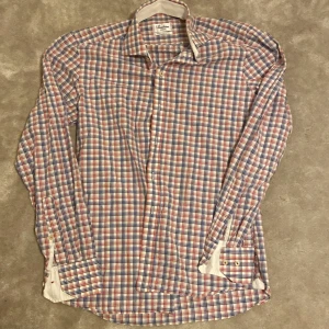 Rutig skjorta från Stenströms Slimline - Rutig skjorta från Stenströms Slimline i 100% tvåfaldig bomull. Långa ärmar med manschett och knappar framtill. Färgerna är vit, blå och röd i ett rutmönster. Är öppen för ett lägre pris vid snabb affär. Om ni har några frågor skriv gärna!