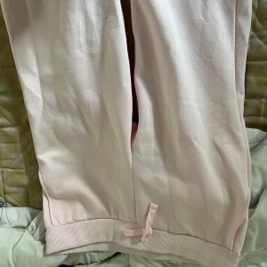 Ljusrosa mjukisbyxor med snörning - Säljer ett par ljusrosa mjukisbyxor med ribbade muddar och snörning vid benslut. Byxorna är i mjukt material och har en avslappnad passform, perfekta för chill dagar eller när du vill vara extra bekväm.
