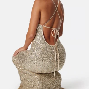 Glittrig långklänning med öppen rygg - Säljer min balklänning i champagnefärg med smala axelband som korsas i ryggen och knyts. Klänningen har öppen rygg och figurnära passform, perfekt för dig som vill sticka ut. Materialet är täckt av paljetter för extra bling❤️kläningen är köpt för 1600 (endast använd en gång)