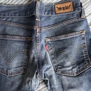 Levi's Patty Anne blå jeans slim fit - Snygga blå Levi's Patty Anne jeans med slim fit och raka ben. Klassisk femficksmodell med kontrastsömmar och ikonisk röd Levi's-tagg på bakfickan. Jeansen har en cool tvättad look och är tillverkade i slitstarkt denimtyg.