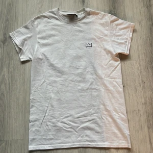 Vit Hov1 t-shirt Vi Dansar Vidare - Intresse koll, kan sälja om vi kommer överens om bra pris. Vit t-shirt från Hov1 med liten krona broderad på bröstet och färgglad turnétext på ryggen. Modellen är klassisk med rund hals och korta ärmar, tillverkad i mjuk bomull. Perfekt för dig som gillar svensk musik och vill ha något unikt i garderoben. 
