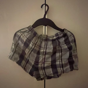 Rutiga loose shorts i bomull - Säljer ett par rutiga shorts i mjuk bomull med loose passform. De har elastisk midja och ett avslappnat snitt, perfekta för varma dagar. Färgerna går i grått, blått och vitt, vilket ger en chill vibe. Perfekta för sommaren eller när du bara vill vara bekväm.