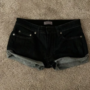 Svarta jeansshorts från Filippa K - Snygga mörkblå low waist jeansshorts från Filippa K med klassisk femficksdesign och uppvikta benslut. Shortsen har normal passform och är perfekta för varma dagar. Tidlös look som funkar till allt, med robust denimkänsla och diskreta sömmar.