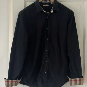 Burberry brit skjorta - Svart klassisk skjorta från Burberry brit i storlek XL (XL/L). Kan behöva strykas men annars i gott skick! Nypris: 3400kr. Vårt pris: 899kr. Hör av er vid frågor/fler bilder!