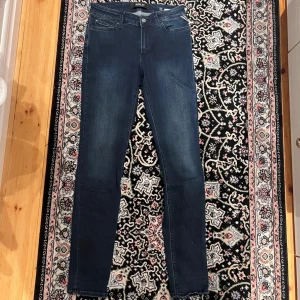 Mörkblå slim jeans från Replay 27/30 - Snygga mörkblå skinny jeans från Replay med klassisk femficksdesign och diskreta slitningar. Jeansen har normalhög midja och är tillverkade i stretchigt denim för en tight och bekväm passform. Perfekta till sneakers eller boots.
