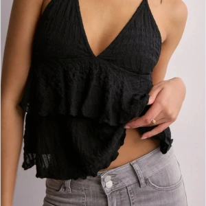 Svart volangig halterneck linnetopp - Säljer en svart linnetopp med volanger och djup v-ringning. Använt en gång då den är lite för liten på mig. Varan finns inte på Nellys hemsida längre. Ordinarie pris 300. Pris kan diskuteras.