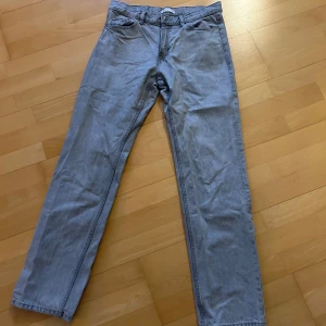 Grå jeans från Gina Tricot storlek 38 - Snygga grå jeans från Gina Tricot i rak modell. Klassisk femficksdesign, bälteshällor och knappgylf. Jeansen har en stilren look och passar perfekt till en avslappnad outfit. Materialet är mjukt och bekvämt denim.