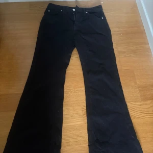 Svarta bootcut byxor från Victoria Beckham - Svarta byxor från Victoria Beckham med bootcut-silhuett. Klassisk femficksmodell med knapp och dragkedja framtill. Byxorna är tillverkade i mjuk manchester och har en snygg, tidlös look som passar till många olika stilar.
