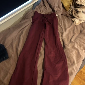 Vinröda mjukisbyxor med snörning - Snygga vinröda mjukisbyxor med breda ben och dragsko i midjan. Perfekta för en chill dag hemma eller när du vill vara bekväm men ändå se stilren ut. Mjukt material och relaxed fit.