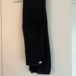 Byxor med slits - Svarta byxor med slits från nakd i stl 32. Dragkedja på sidan