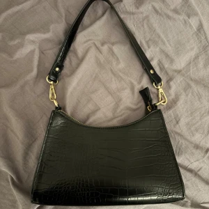 Svart axelväska i croco-imitation - Säljer en snygg svart väska tror den är från Nelly, säljer då den inte kommer till användning längre den är använd ett fåtal gånger