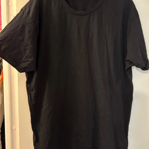 Svart slim fit t-shirt från FSBN strl: XXL - En svart t-shirt från FSBN i slim fit-modell. Klassisk rund halsringning och korta ärmar. Enkel och clean design som funkar till allt. Tillverkad i mjuk bomull för skön känsla hela dagen.