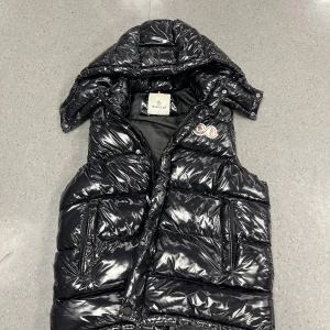 Svart dunväst från Moncler med huva - Jag säljer min moncler väst! Västen är fet använd några månader. Västen sitter lite som M. Inga skador utanför men inuti är de lite dma för bilder, kom på ett pris för snabbaffär !