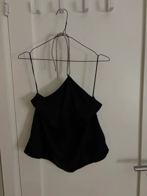 Svart halterneck topp från H&M - Säljer en halterneck topp ifrån H&M☺️ den har små diamanter runt halsen och lite öppen rygg, perfekt nu inför nyår💕