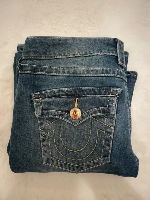 True Religion blå bootcut jeans - Säljer ett par blå jeans från True Religion med bootcut passform och låg midja. Modellen är Joey low Rise flare i storlek 26 , pris kan diskuteras!💗
