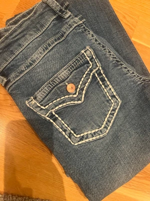 Blå bootcut jeans med vita sömmar - Blå jeans från Gina med vita sömmar på fickorna 