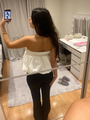 Vit axelbandslös tubtopp med volym - Säljer en vit axelbandslös tubtopp med voluminös och luftig passform. Toppen har en söt v-ringning och veckade detaljer upptill som ger en snygg struktur. Perfekt för dig som vill ha en trendig och luftig look till sommaren.