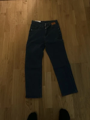 Mörkblå jeans - Snygga mörkblå jeans från Levi's modell 511 med klassisk femficksdesign och knappgylf. Jeansen har en rak och något smalare passform som ger en modern look. Perfekta att matcha med sneakers eller boots för en chill stil.