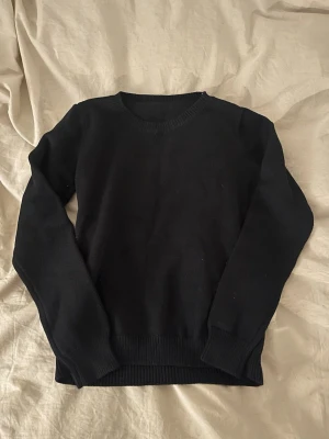 Svart stickad tröja med rund hals - En enkel svart stickad tröja med rundad hals och ribbade muddar vid ärmslut och nederkant. Tröjan har långärmade. Finns ingen etikett 🖤