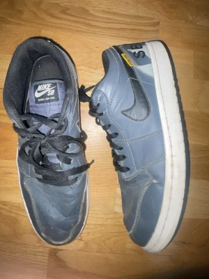 Nike SB Dunk. Custom/limted edition - Nike SB Dunk Low Pro sneakers i blått med svarta detaljer och vit sula. Skorna har klassisk snörning, rund tå och är tillverkade i skinn. Snygg kontrast mellan blå och svart, med SB-logga på hälen och Nike swoosh på sidan.