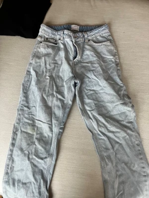 Ljusblå loose fit jeans från H&M - Säljer ett par ljusblå jeans från H&M med loose fit och justerbar midja. Klassisk femficksmodell med dragkedja och knapp framtill. Jeansen har raka ben och är tillverkade i jeansmaterial med kontrastsömmar.