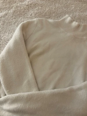 Vit stickad polotröja  - Säljer en vit polotröja i ett mjukt stickat material. Fint sick, tröjan är väl tagit handom därmed inga synliga slitningar i tröjan. Inga noppor eller liknande. 