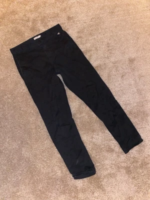 Svarta chinos från Calvin Klein Jeans - Säljer ett par svarta chinos från Calvin Klein Jeans med stilren CK-brodyr vid fickan. Byxorna har normal passform, raka ben och är gjorda i mjuk bomull. Perfekta för dig som gillar klassisk och enkel stil med en touch av designer.