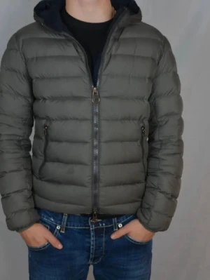 Mörkgrå dunjacka från Colmar - Säljer en mörkgrå dunjacka från Colmar med huva och dragkedja framtill. Jackan har quiltad design, två sidofickor med dragkedja och Colmar-logga på ärmen. Perfekt för kyliga dagar och riktigt skön att bära.