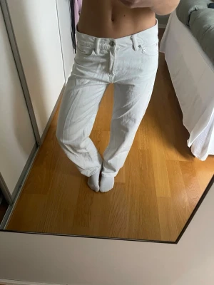 Vita raka jeans från Levi's - Säljer ett par vita jeans från Levi's med rak passform och klassisk femficksdesign. Byxorna har normal midja och är tillverkade i ett slitstarkt bomullsmaterial. Perfekta för dig som gillar en clean och enkel stil.